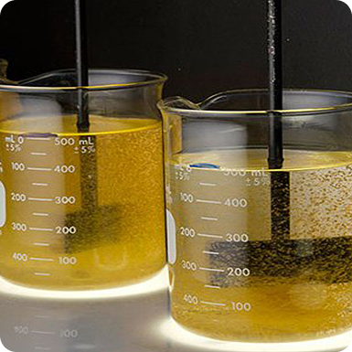 Two beakers containing a yellow liquid being stirred.